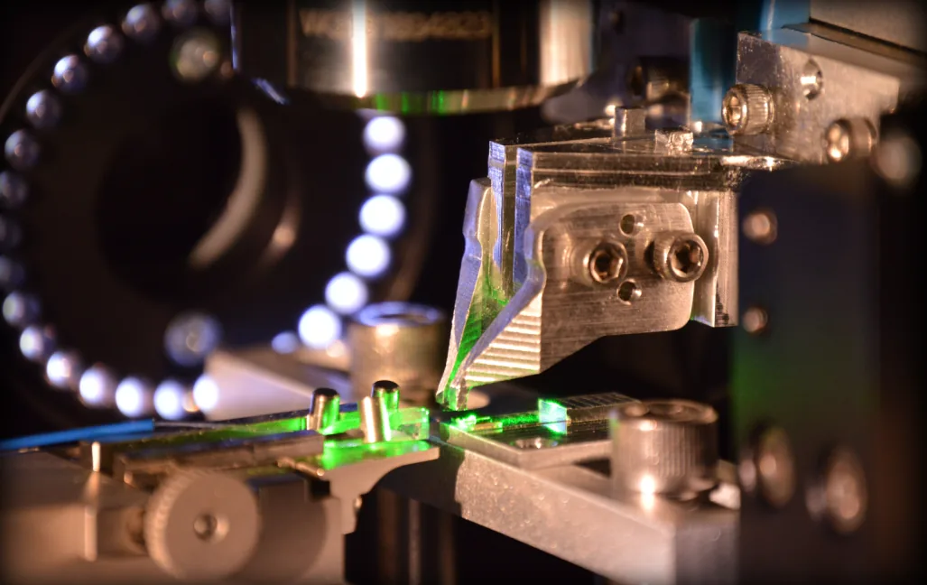 Photonic chip packaging station with green laser coupling